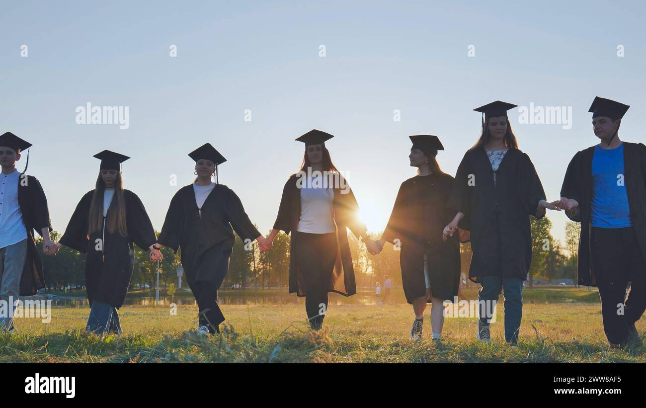 College graduates walk at sunset holding hands Stock Photo - Alamy