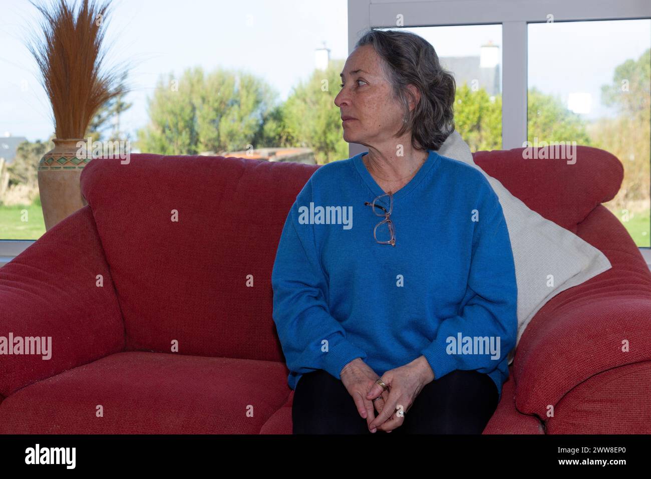 Senior woman alone of sofa Stock Photo