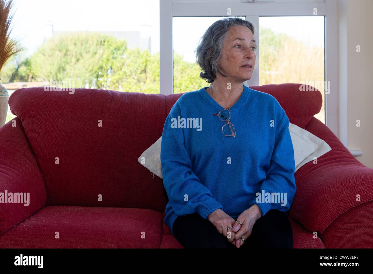 Senior woman alone of sofa Stock Photo