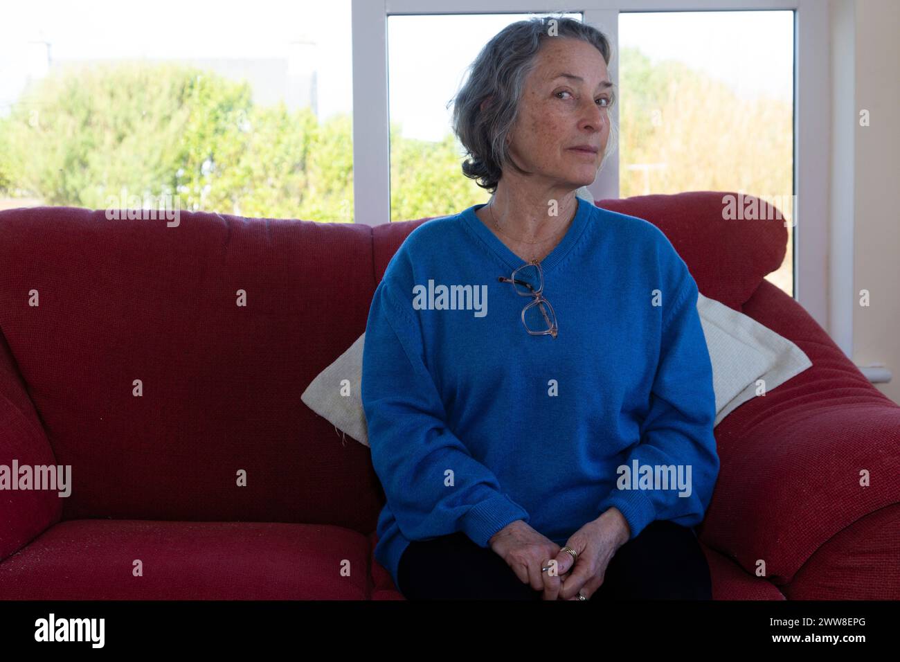 Senior woman alone of sofa Stock Photo