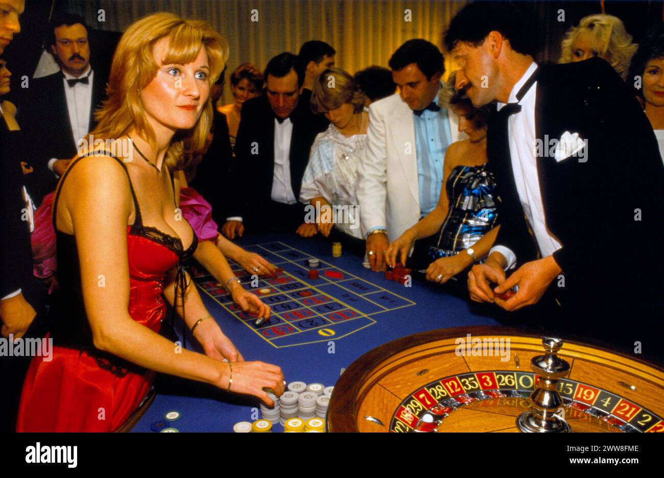 Female croupier, wearing a burlesque corset basque people playing roulette, gambling in Britain, at the annual  SPARKS charity ball at the Hilton Hotel. London, England circa December 1992. 1990s UK HOMER SYKESotel. Stock Photo