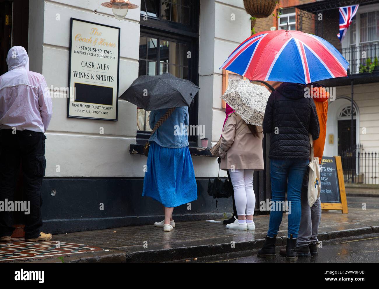 People watch the coronation of King Charles III on screen at a pub in central London. Stock Photo