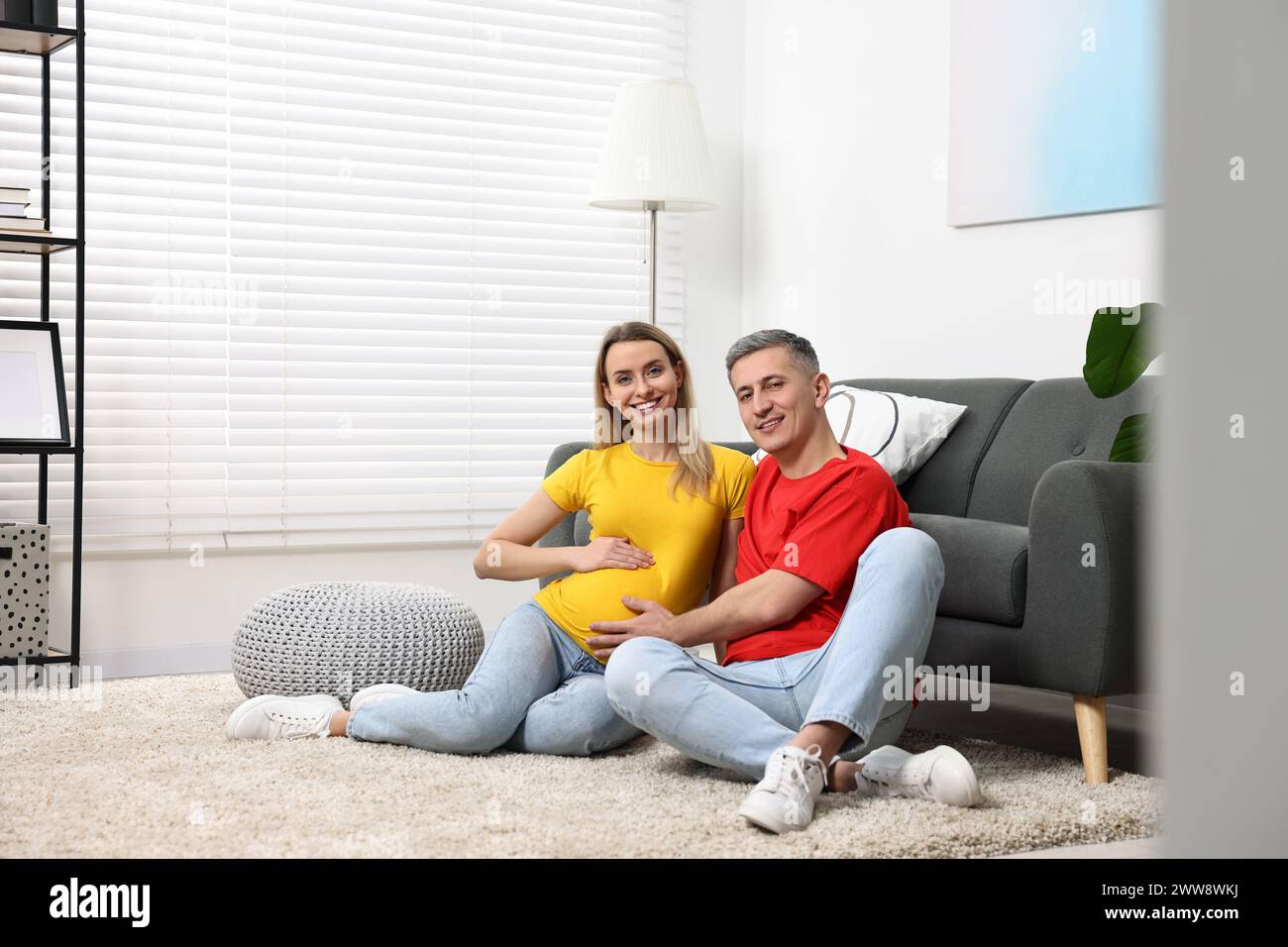 Young family housing concept. Pregnant woman with her husband on floor at home Stock Photo