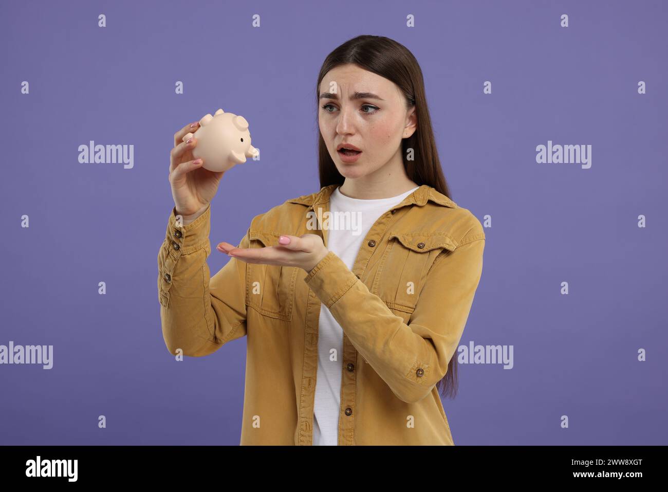Sad woman with piggy bank on purple background Stock Photo - Alamy