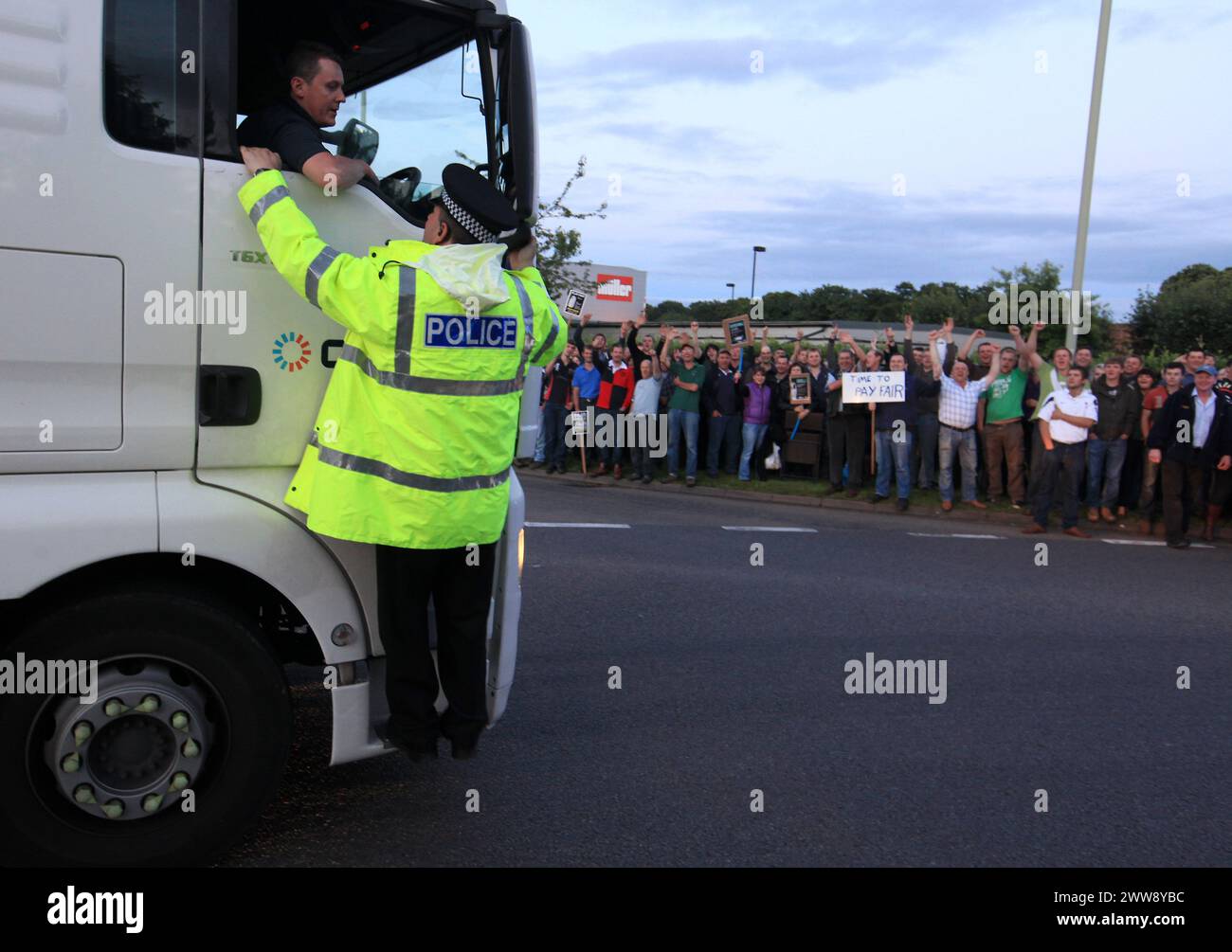 22/07/12..As protesters jeer at the lorry, a police office talks to the milk tanker driver outside the Muller processing plant in Market Drayton. ..On Stock Photo