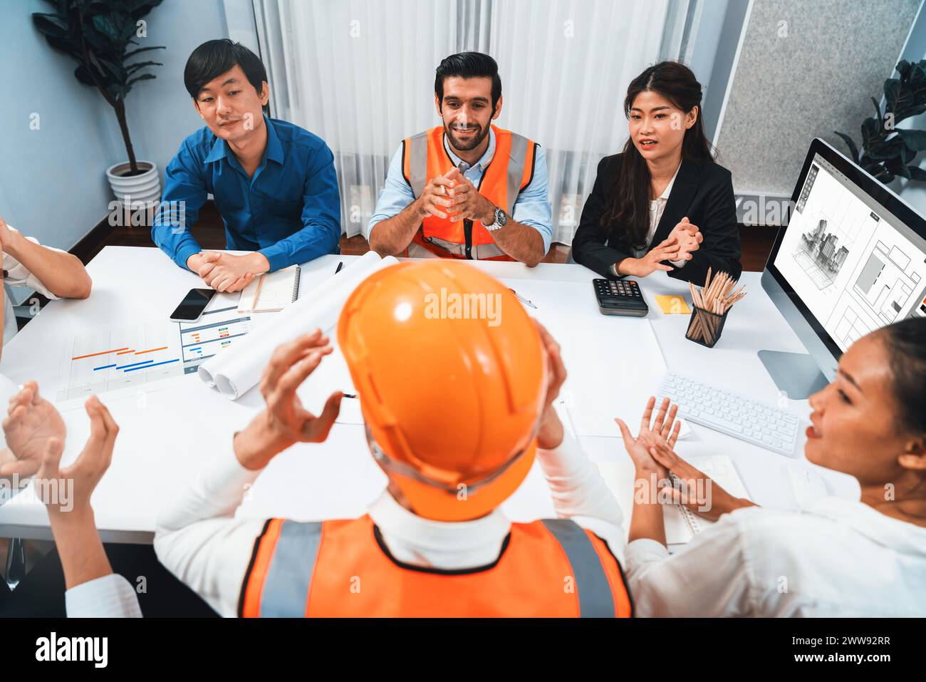 Diverse group of civil engineer and client feels excited and applauding after successful agreement on architectural project, review construction plan Stock Photo