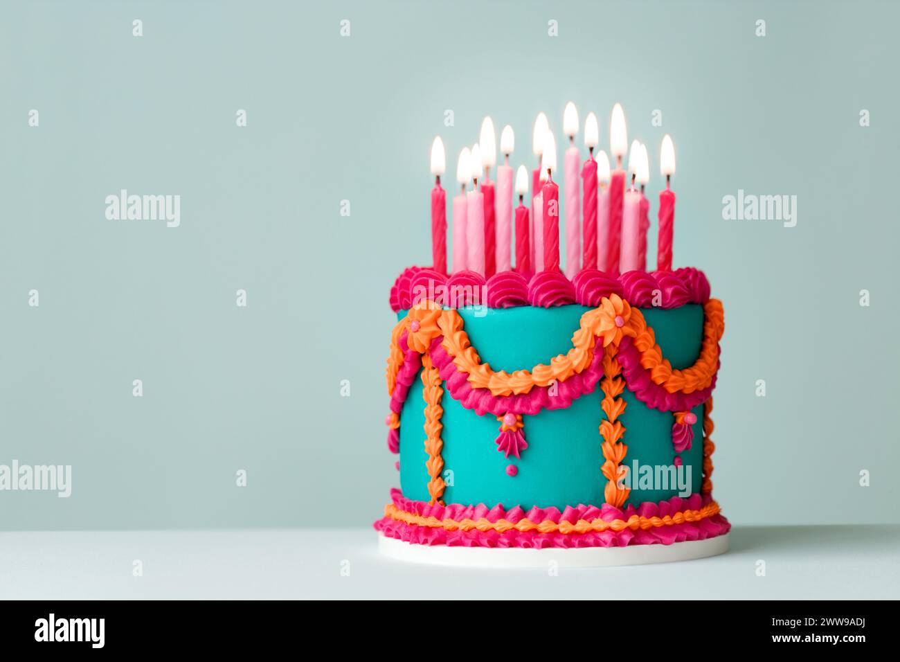 Elaborate jade colored birthday cake with pink and orange piped vintage style frills and birthday candles Stock Photo