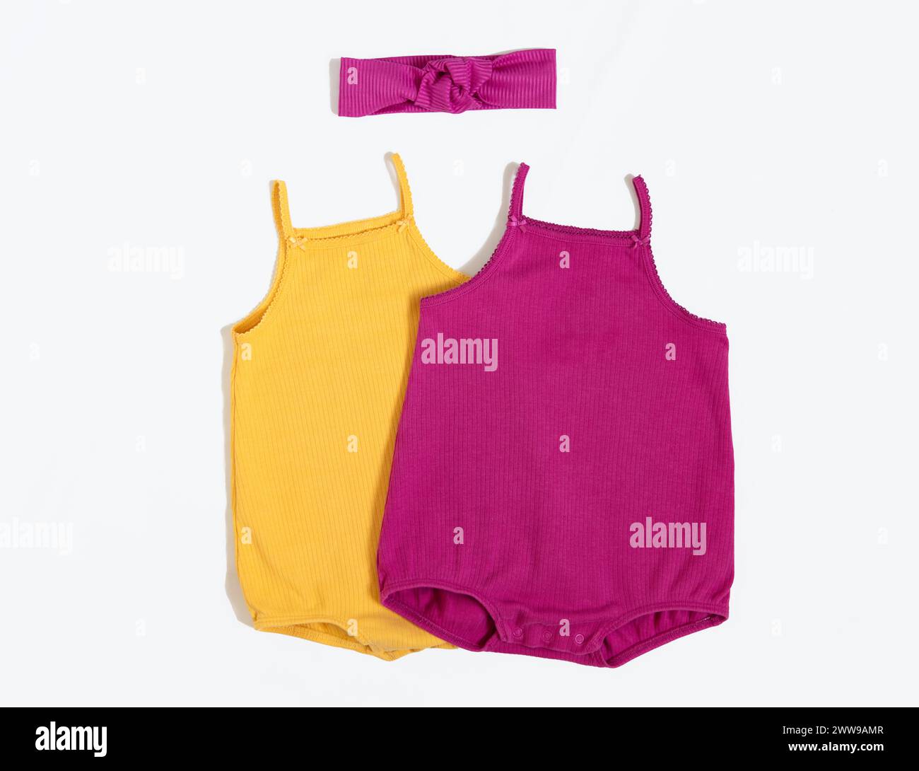 Summer outfit. Baby vest bodysuit yellow and pink color with head accessories. Top view, flat lay on white. Stock Photo