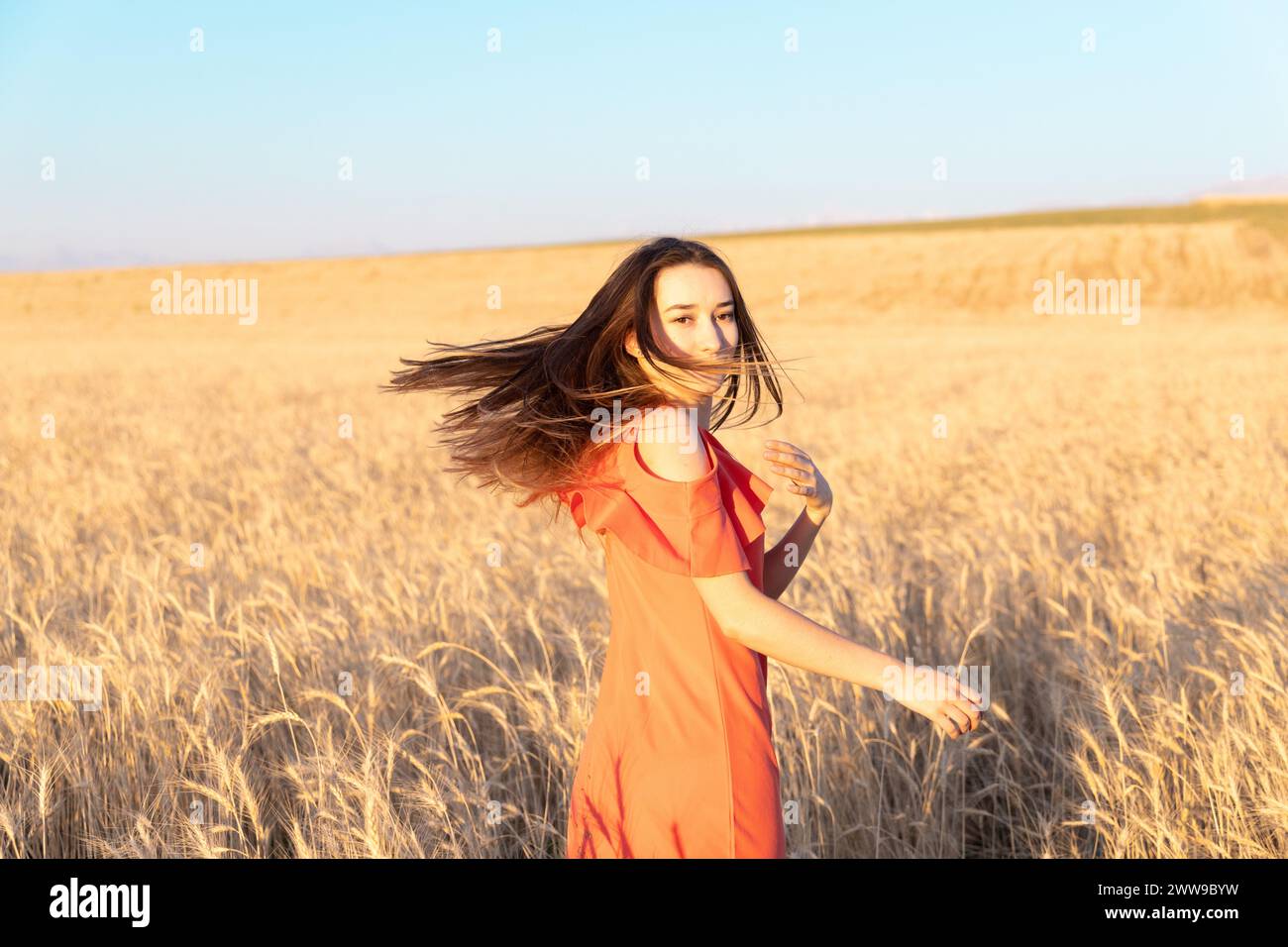 Young woman in the wheat field. Look back. Finding inner balance concept. Copy space. Stock Photo