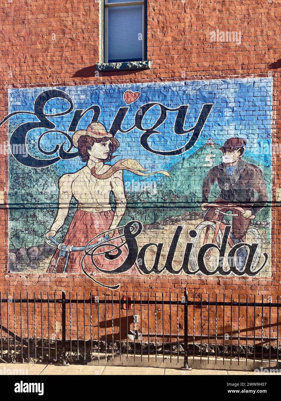 Enjoy Salida mural on exterior of red brick building with figure wearing a Covid-19 mask in Salida, Colorado on Dec. 27,2020 Stock Photo
