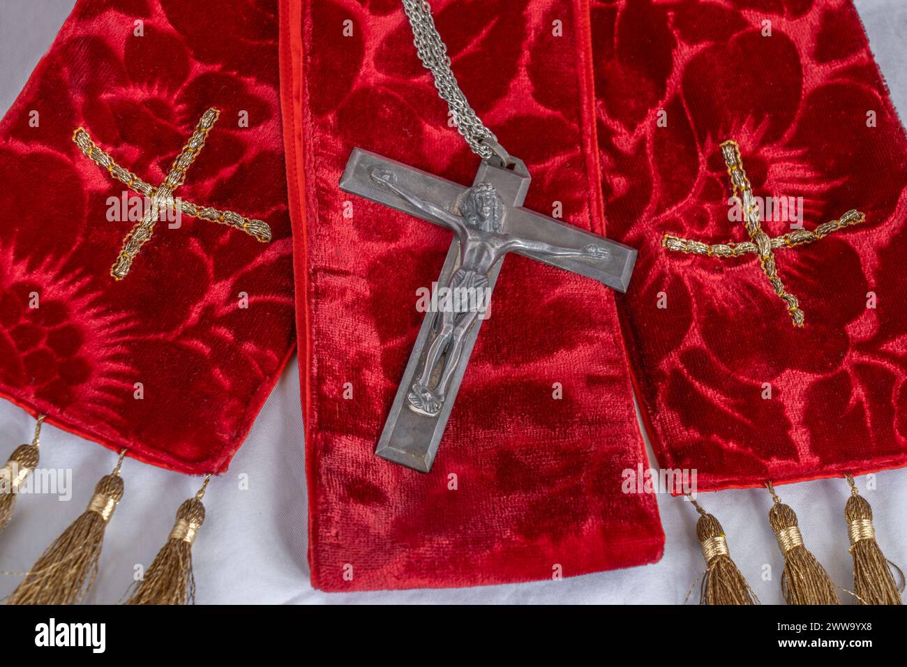 Closeup red vestments, stole, crucifix for Holy Week, Palm Sunday, Pentecost, Maundy Thursday, & church Easter Festivals with gold crosses. Stock Photo