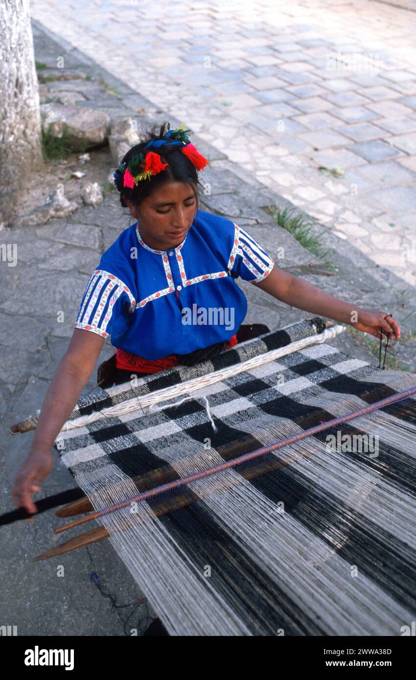 Tzotzil speaking Maya Indian woman from San Juan Chamula weaves traditional brocaded designs on her traditional backstrap loom,  Monday, December 20, 1976 in San Juan Chamula, Chiapas Central Highlands, southern Mexico. Stock Photo