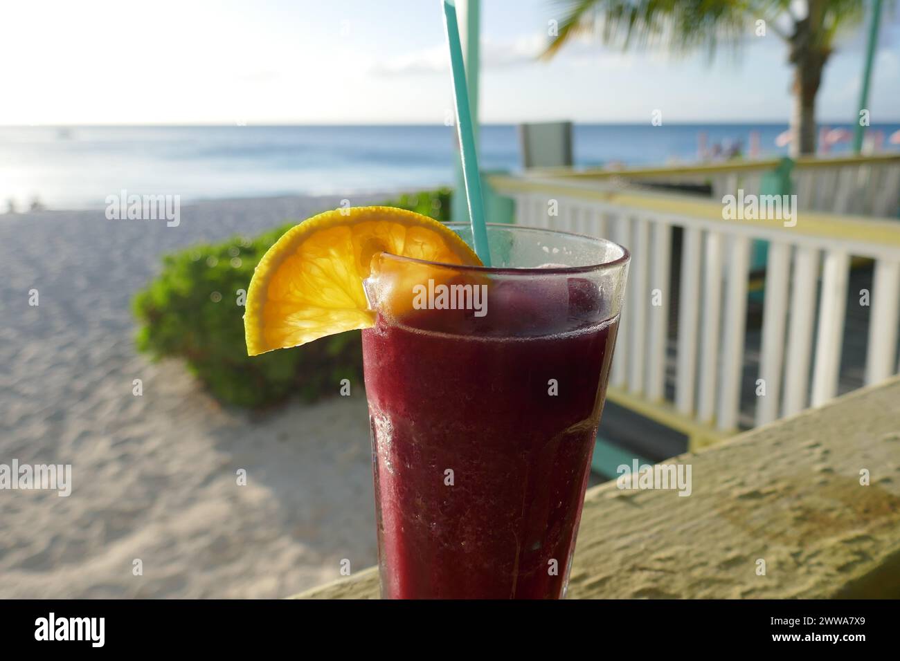 Tropical refreshing frozen fruity drink in drinking glass and beach vacation resort out of focus in background Stock Photo