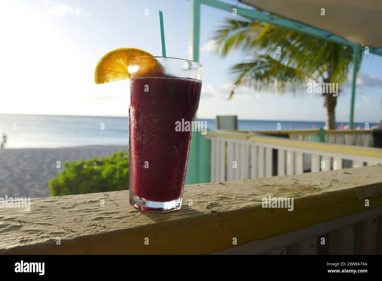 Tropical frozen drink with orange slice and ocean beach scene in background Stock Photo