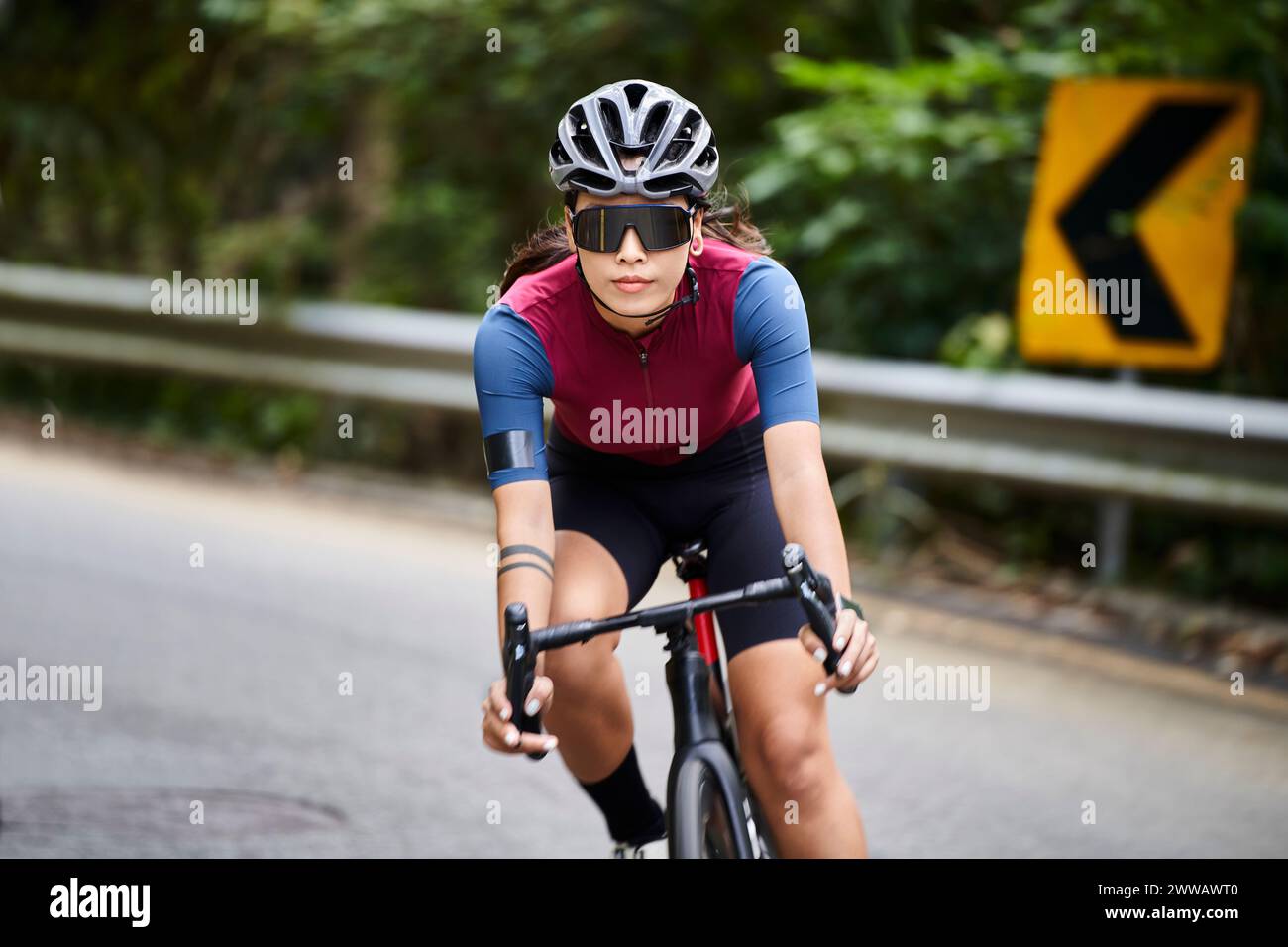 young asian woman female cyclist riding bicycle outdoors on rural road Stock Photo
