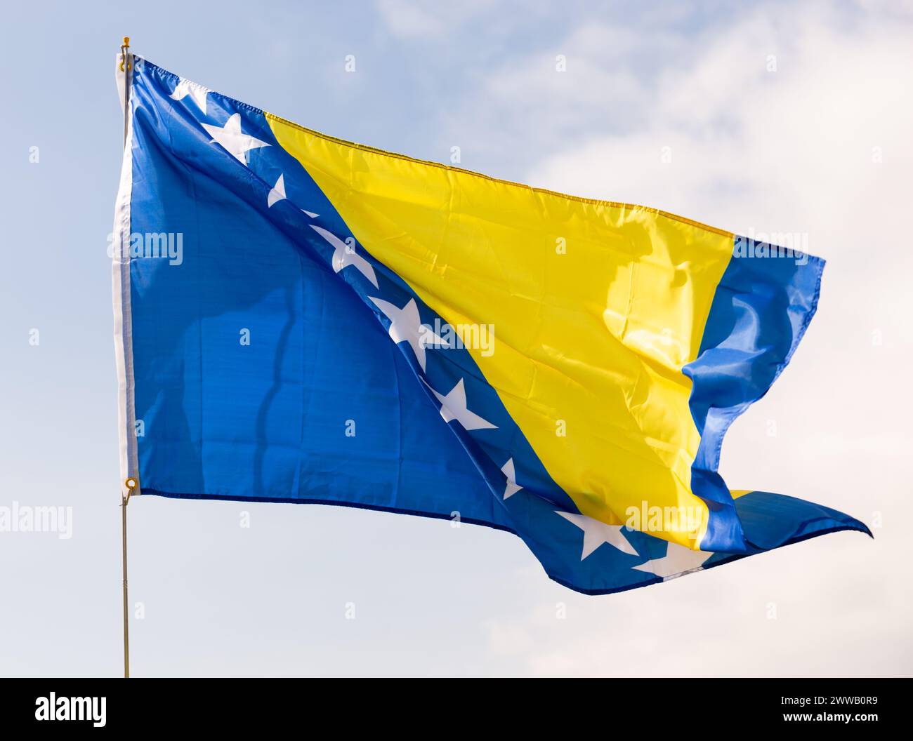 Flag of Bosnia and Herzegovina flying against blue sky Stock Photo - Alamy