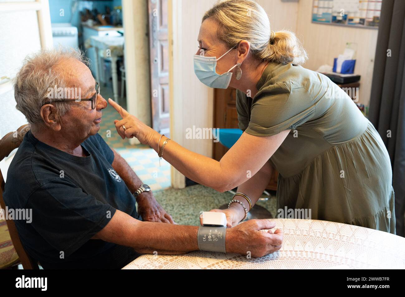 90 year old senior with his home care nurse taking his blood pressure. Stock Photo