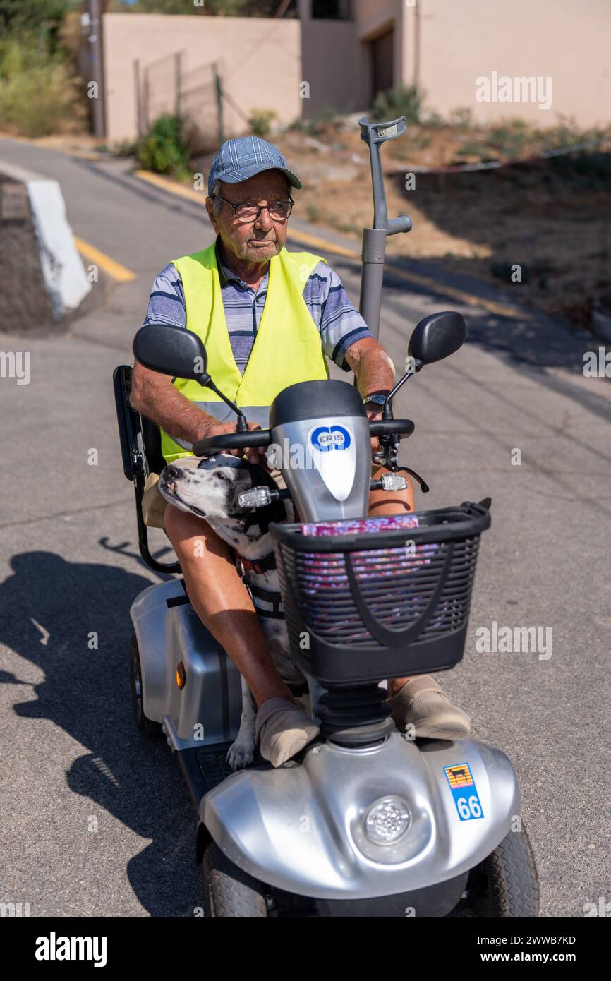 90-year-old senior walking on his electric scooter, with his dog. Stock Photo