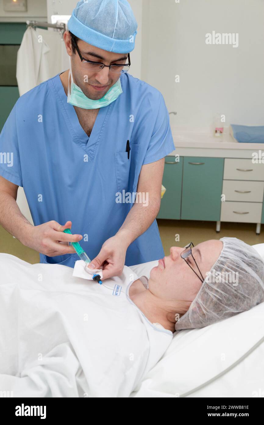 Epidural. Anesthesiologist injecting analgesic product through the ...