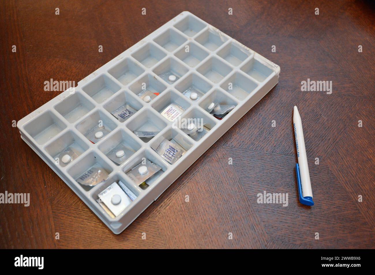 HAD (Hospitalization At Home). Follow-up of an elderly patient at home by a nurse. Pillbox and pen on a table. Stock Photo