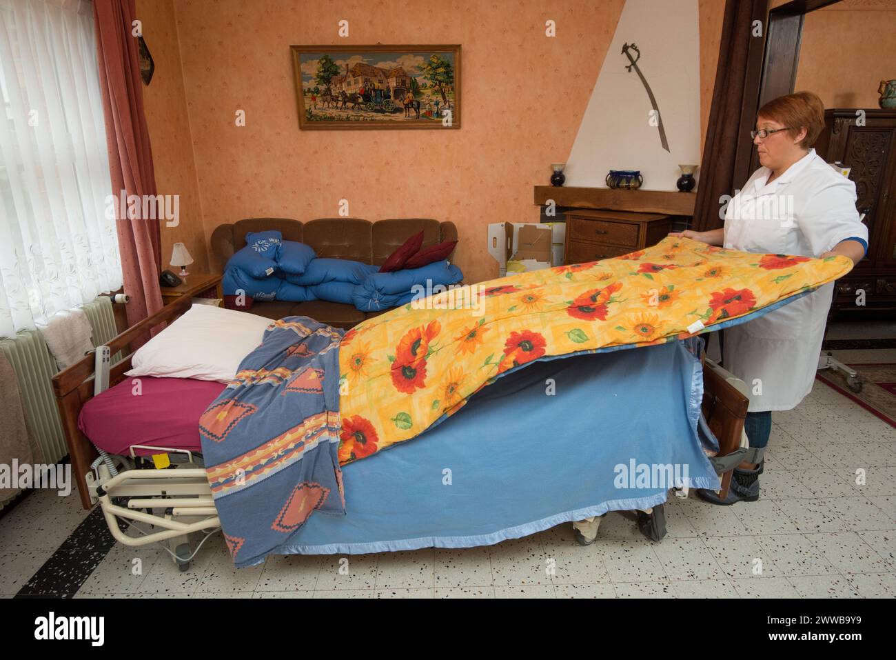 HAD (Hospitalization At Home). Follow-up of an elderly patient at her home by a caregiver. Nursing assistant making the bed. Stock Photo