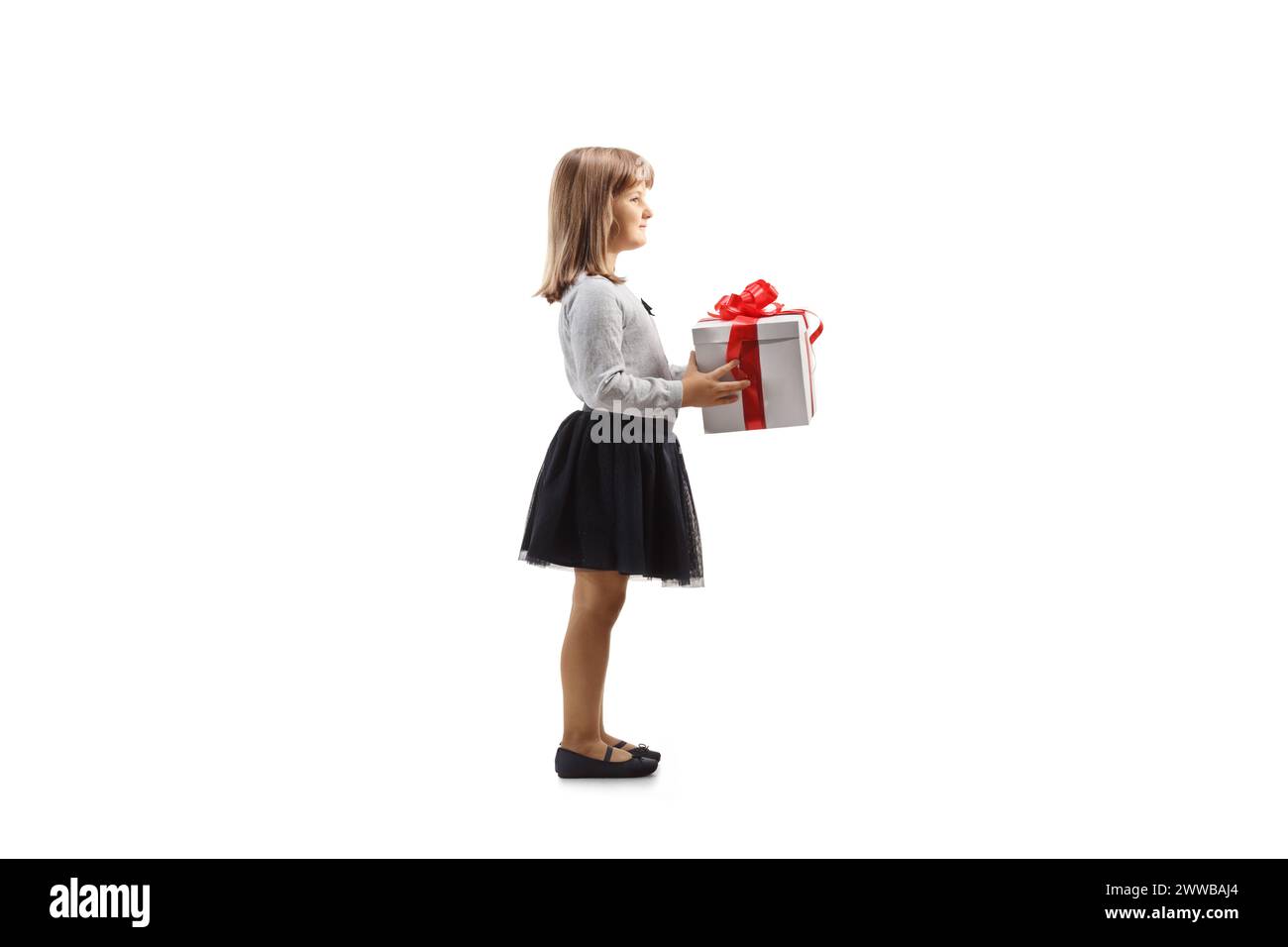 Full length profile shot of a little girl holding a gift box isolated ...