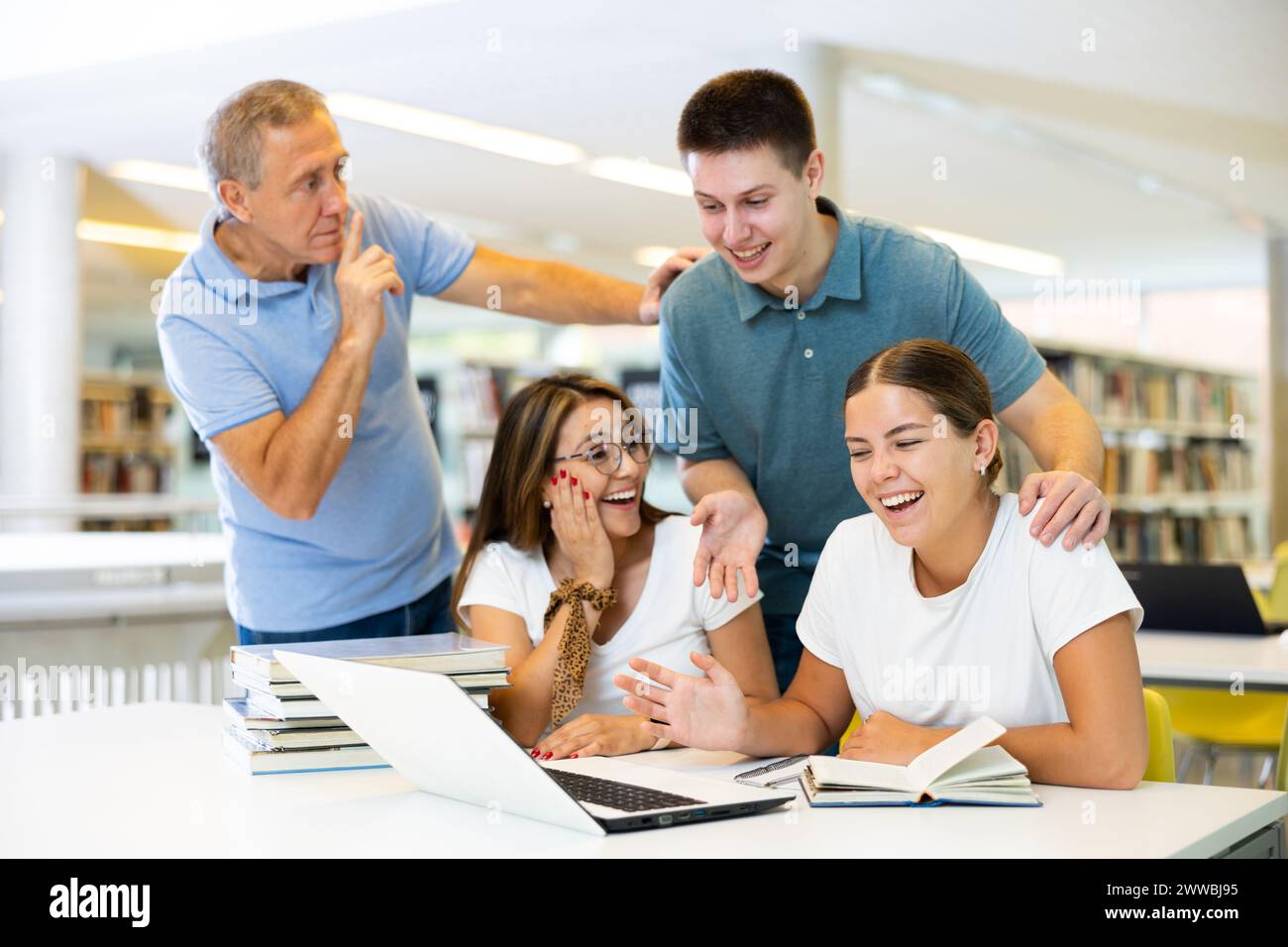 Mature man tells a group of young students to be quiet Stock Photo