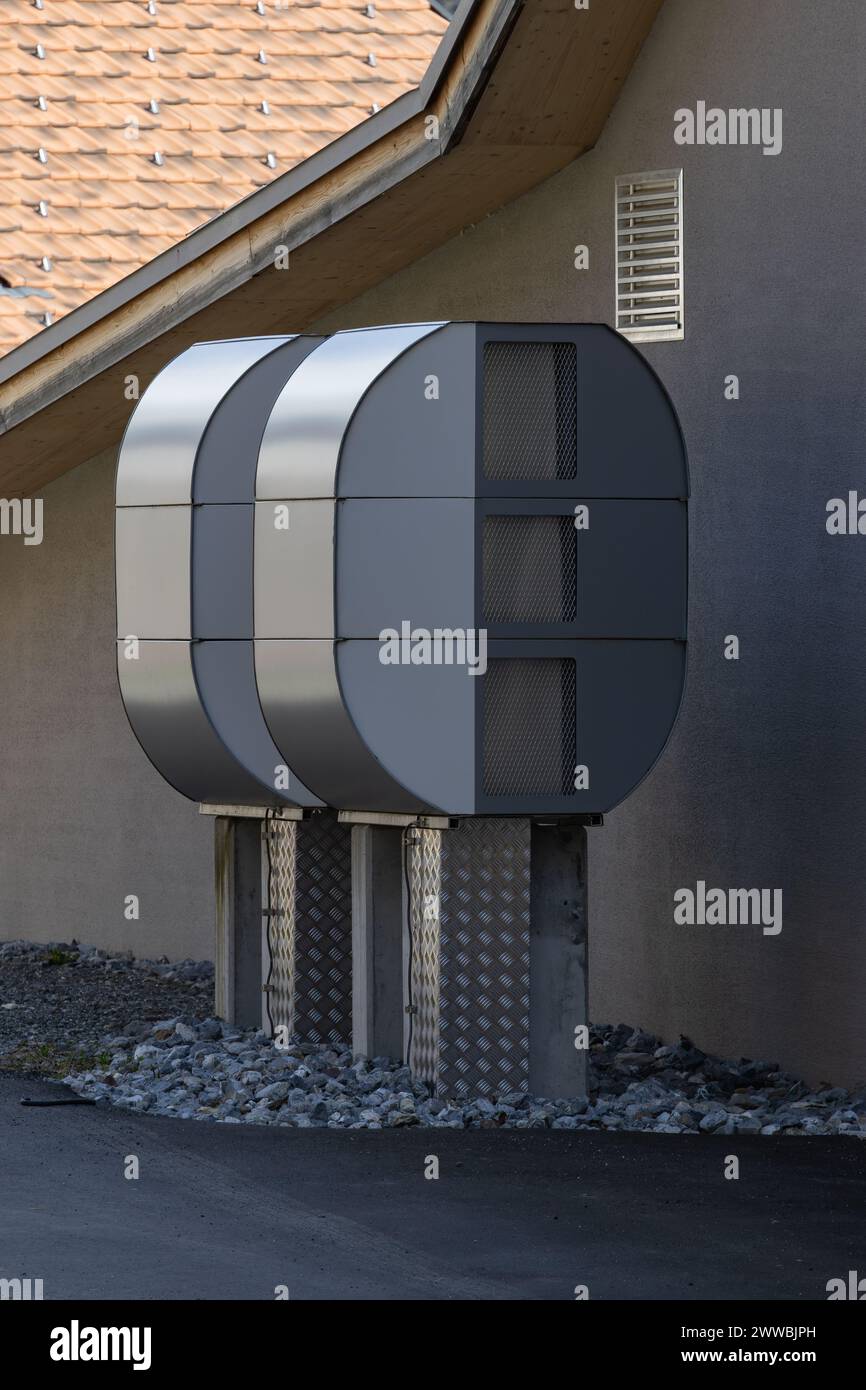 two large heat pumps in front of a gray house wall Stock Photo