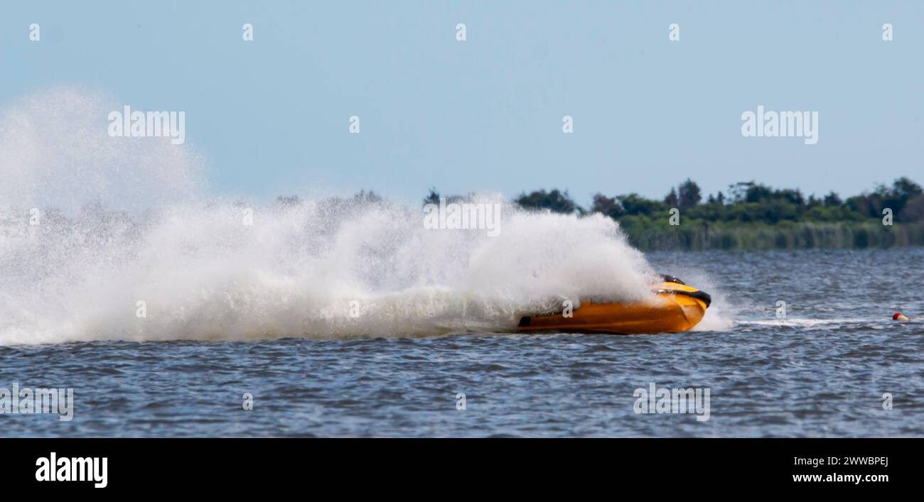 Horizontal view of on jet ski turning leaving a wall of water as a wake in the bay off the coast of Long Island. Stock Photo