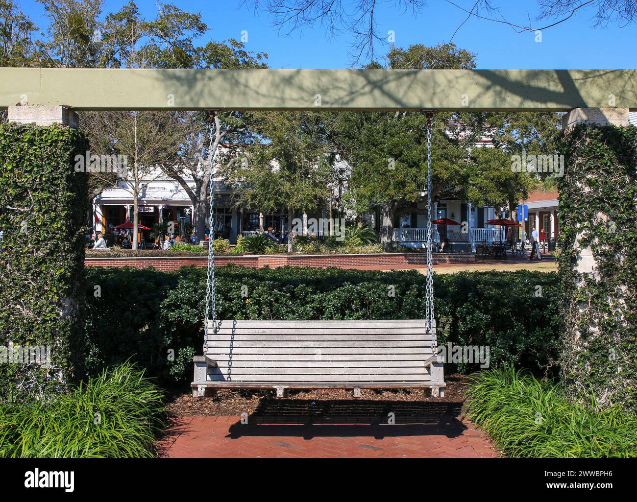 Wood bench swing hanging in Henry Champbers Park with shops in the background in Beaufort South Carolina Stock Photo