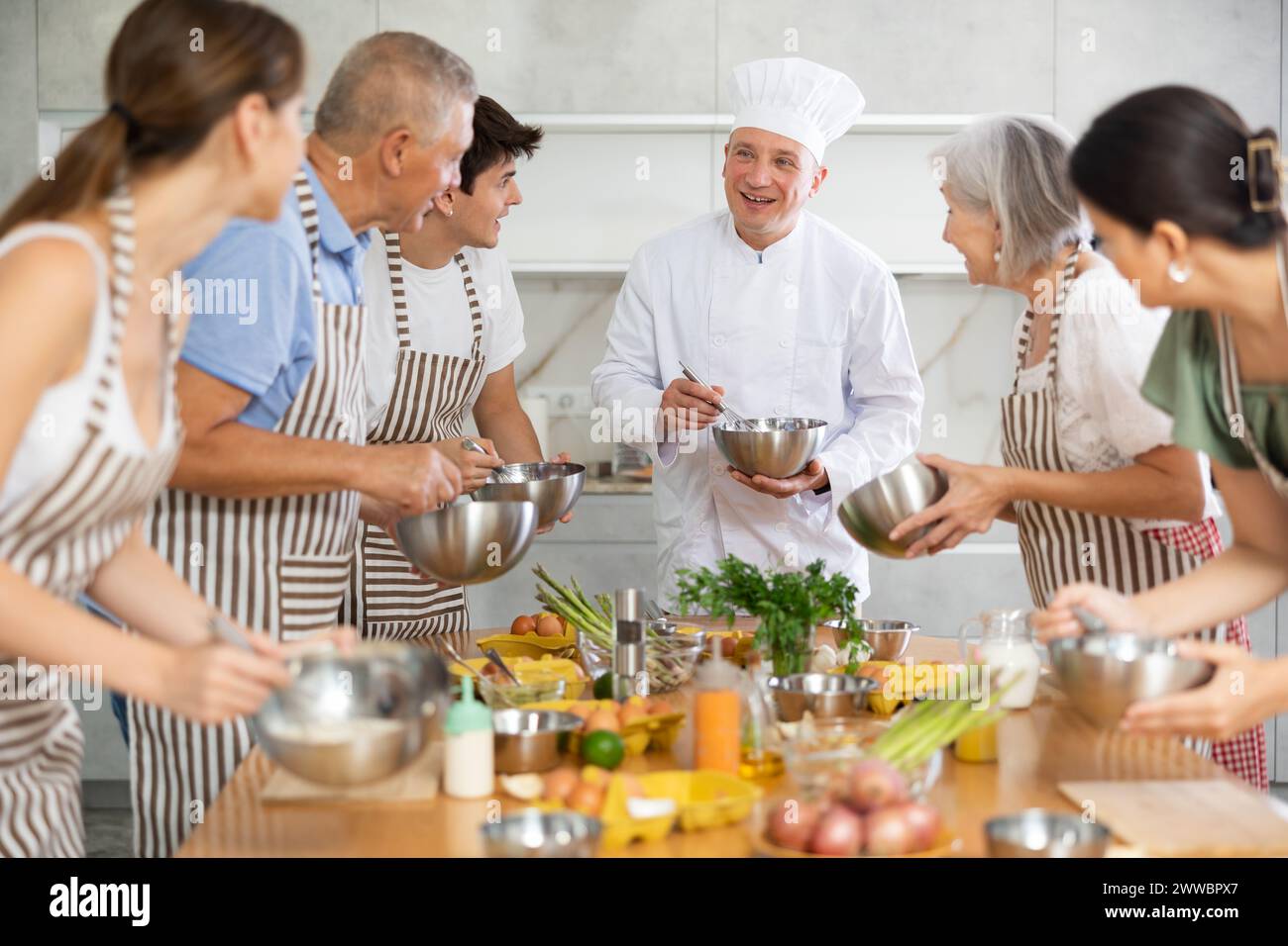 Cooking course male chef in cook uniform teaches young people cooking