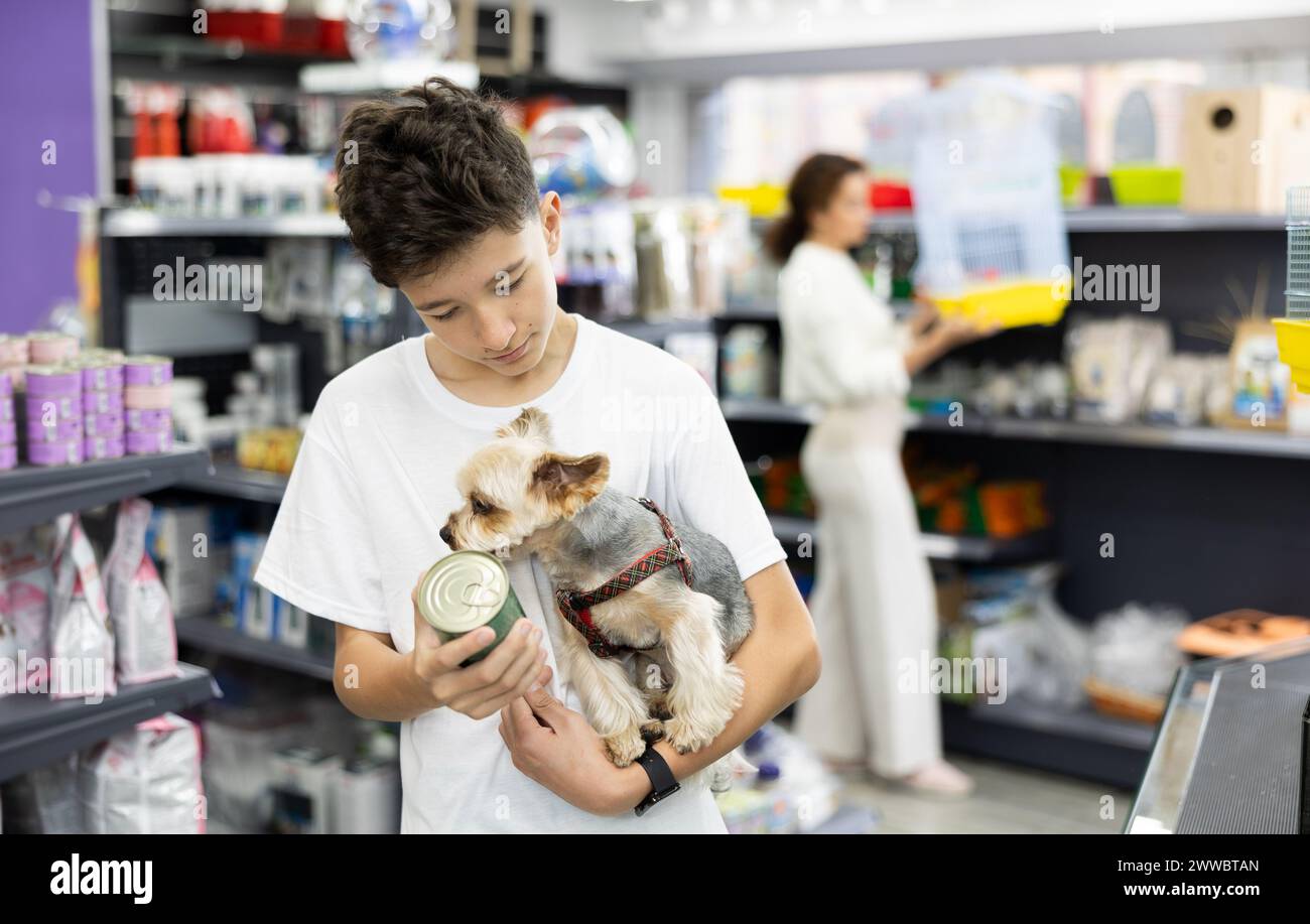 Boy with dog Yorkshire terrier in arms and read composition of product at packaging of dog dry food Stock Photo