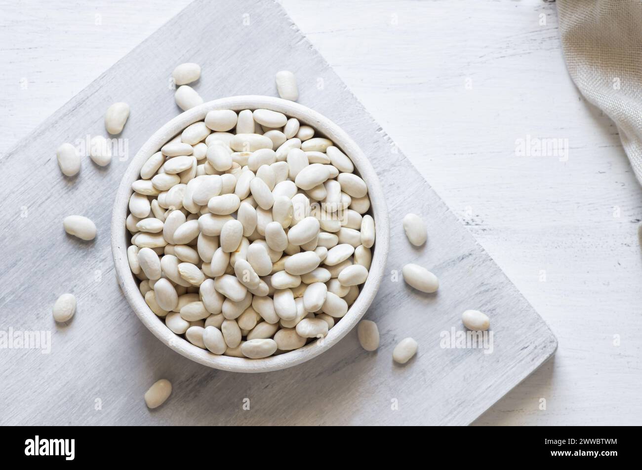 Uncooked dried white haricot beans in bowl or spoon on table. Heap of ...