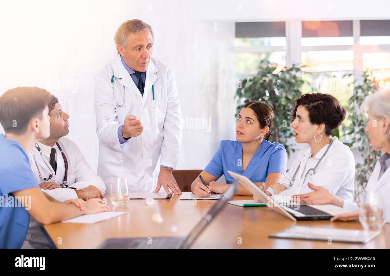 Elderly head doctor conducting medical council with colleagues Stock Photo