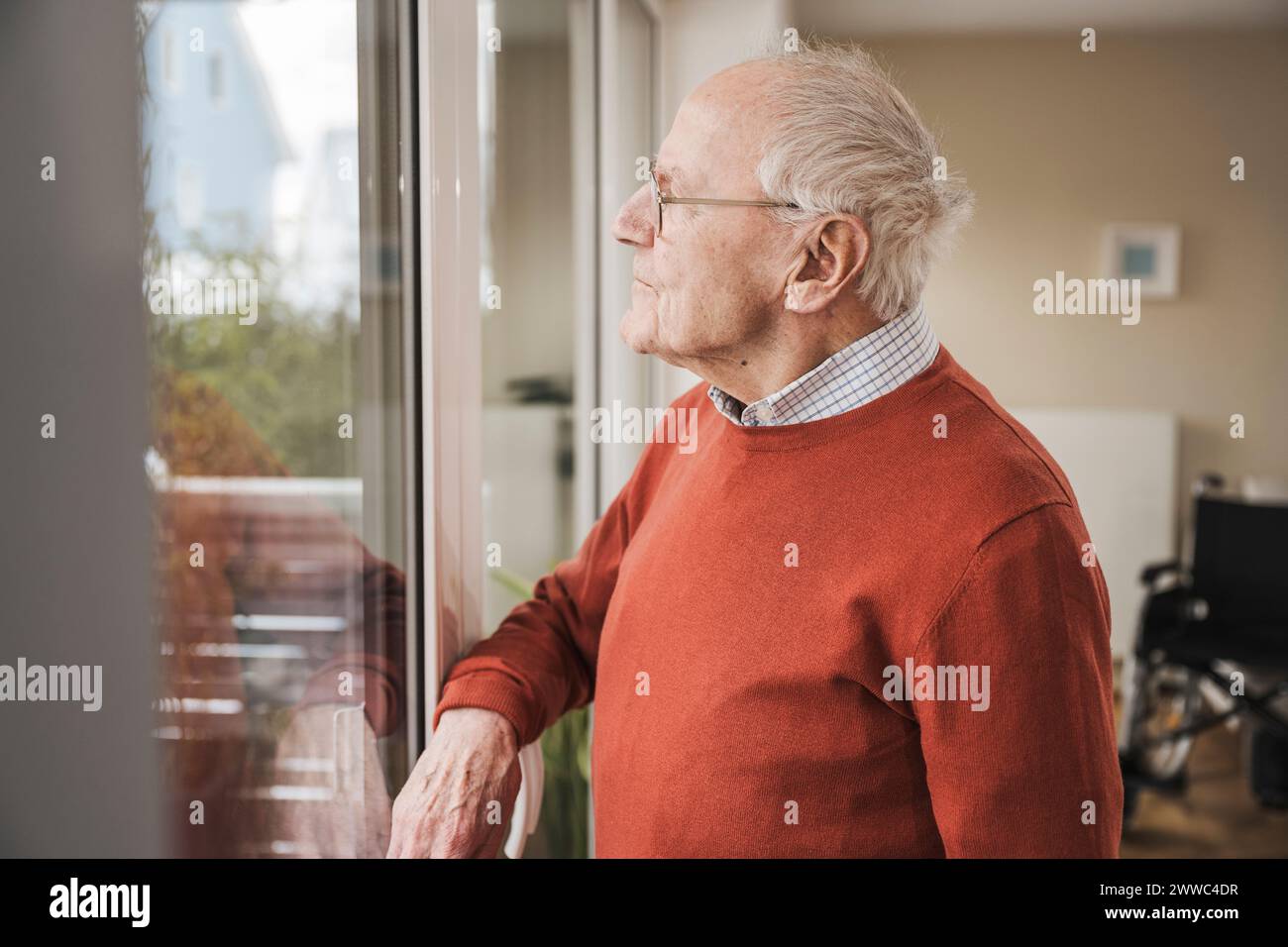 Thoughtful senior man looking through window Stock Photo