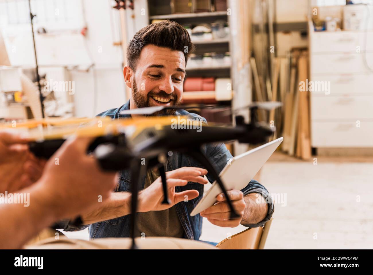 Happy engineer programming drone with tablet PC at workshop Stock Photo