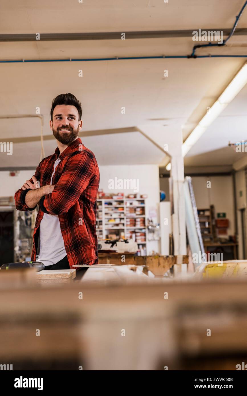 Smiling carpenter standing with arms crossed at workshop Stock Photo
