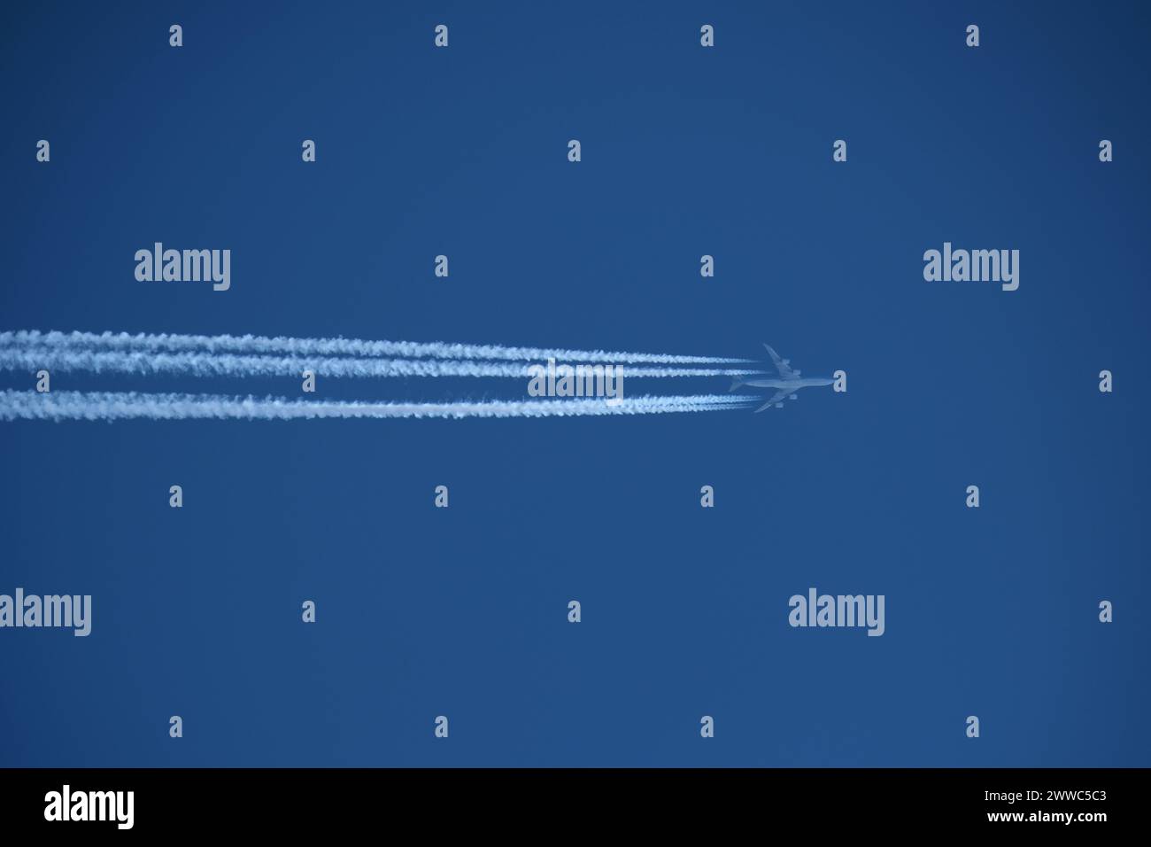 Airplane in the blue sky with contrail Stock Photo - Alamy