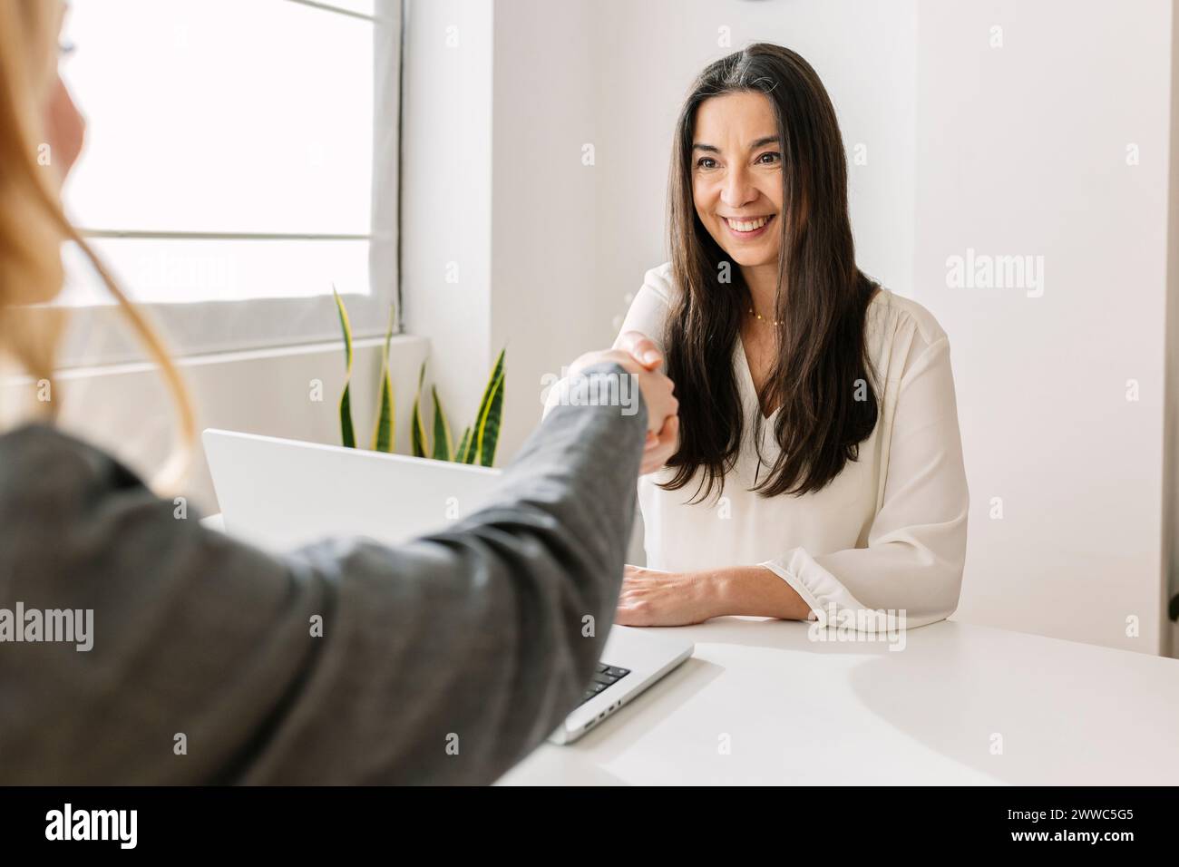 Smiling recruiter shaking hands with candidate at office Stock Photo