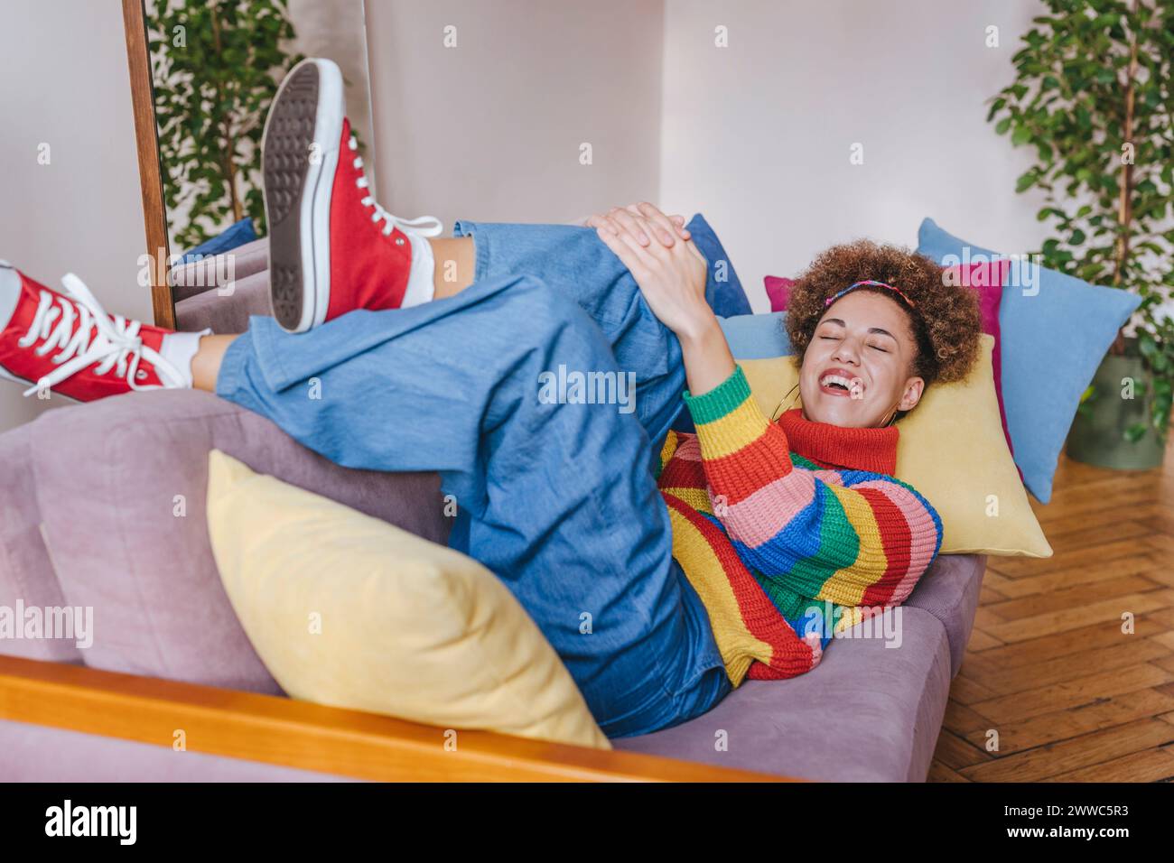 Smiling young woman lying on sofa at home Stock Photo