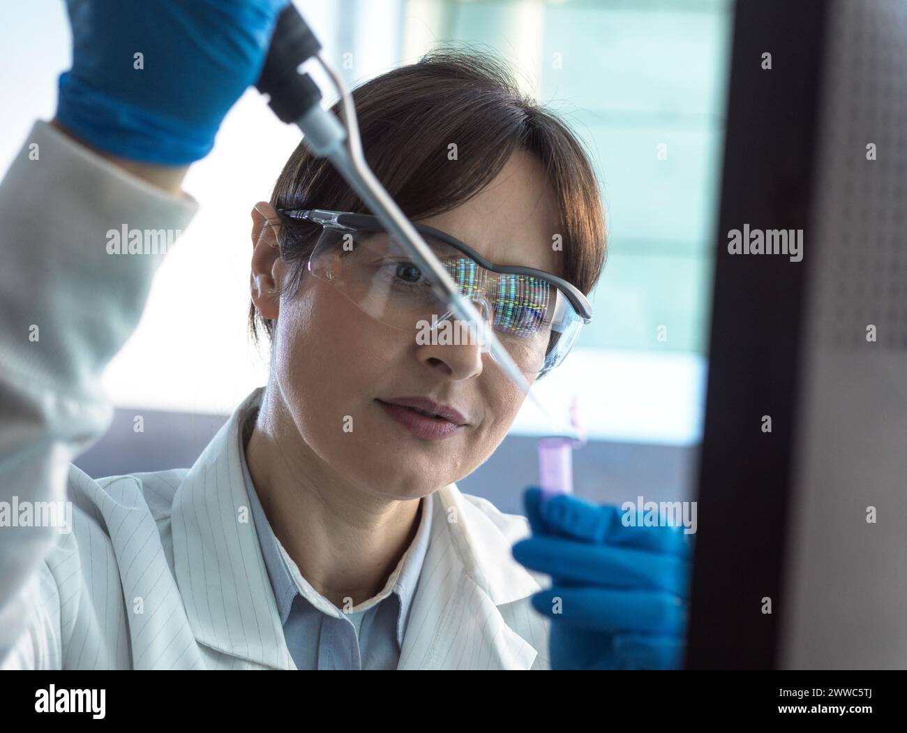 Scientist pipetting DNA sample into eppendorf tube at laboratory Stock Photo