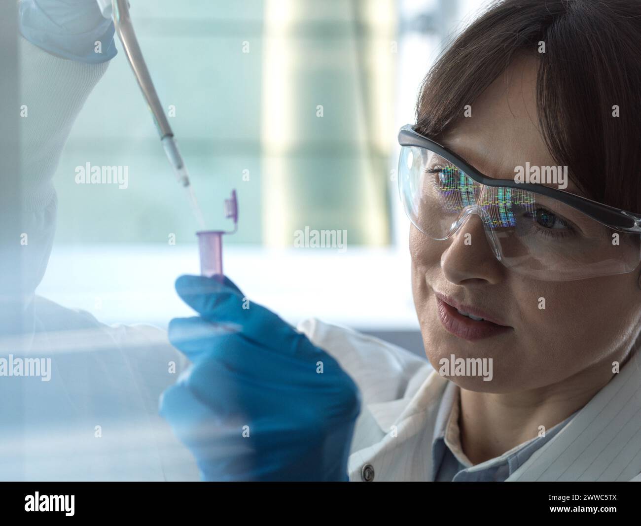 Scientist pipetting DNA sample into eppendorf tube in laboratory Stock Photo