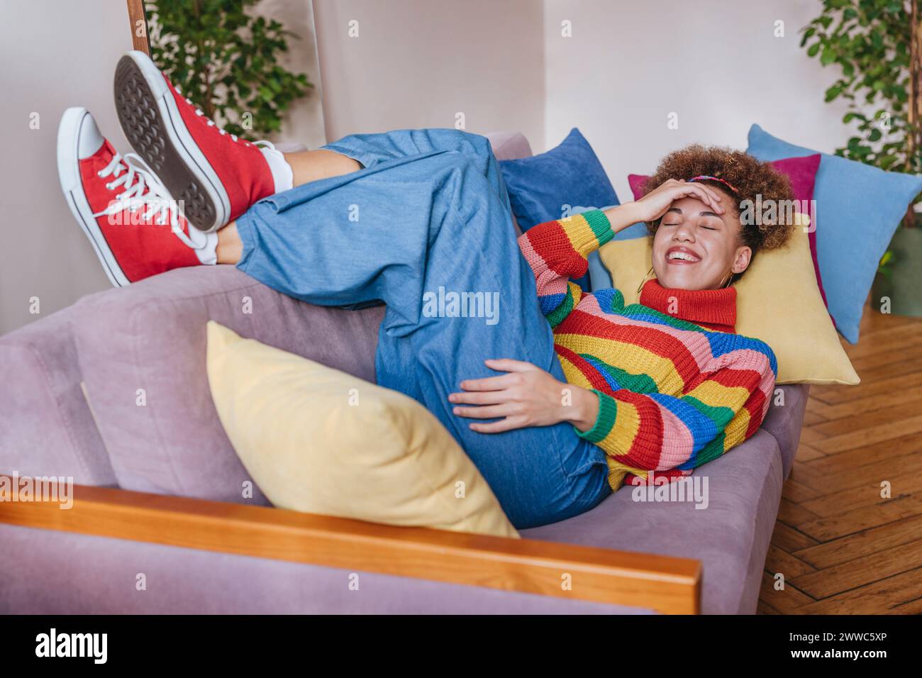 Happy young woman touching forehead and lying on sofa at home Stock Photo