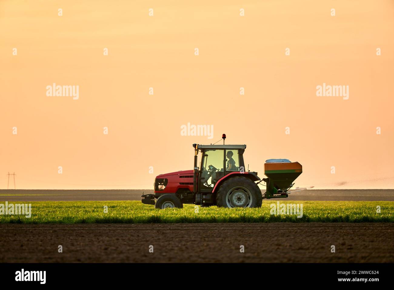 Farmer driving tractor and working on field at sunset Stock Photo - Alamy