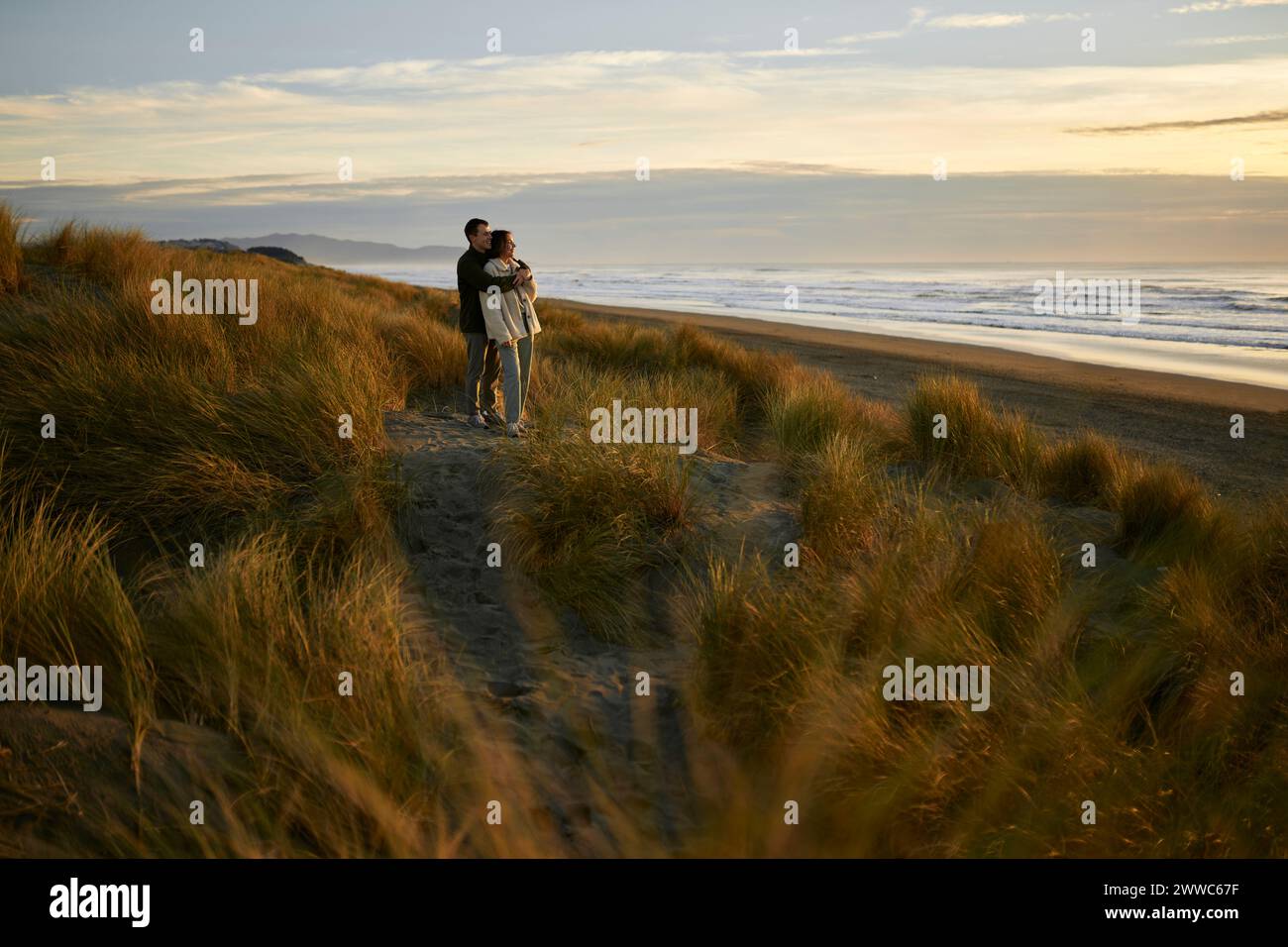 Young man embracing girlfriend at beach Stock Photo