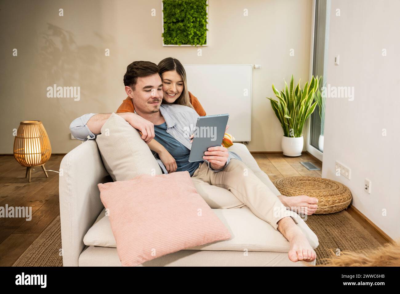 Smiling young couple using tablet PC on sofa Stock Photo