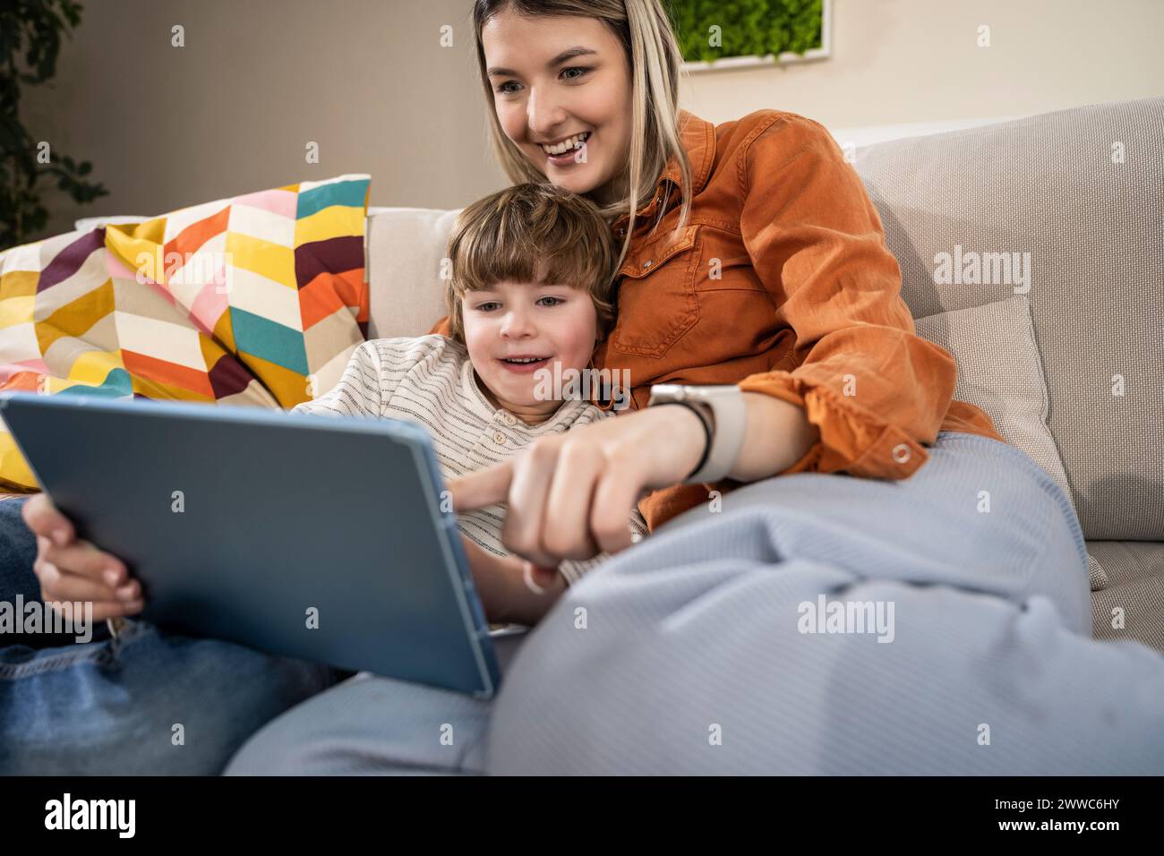 Happy boy with mother using tablet PC at home Stock Photo
