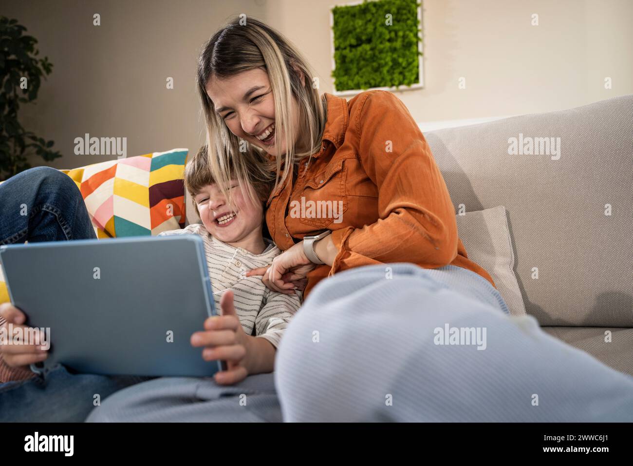 Cheerful boy with mother using tablet PC at home Stock Photo
