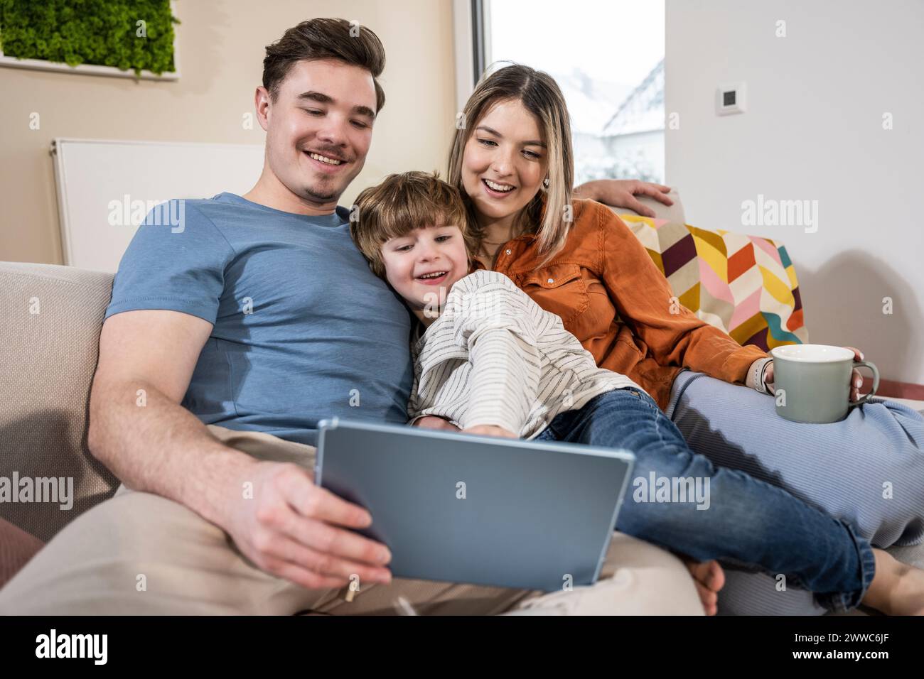 Happy family using tablet PC on sofa at home Stock Photo