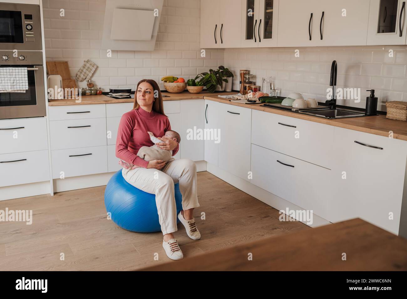 Woman sitting with baby daughter on fitness ball Stock Photo